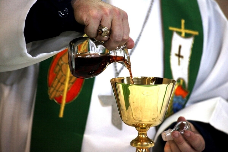 Priest pouring sacramental wine from a cruet into a chalice.