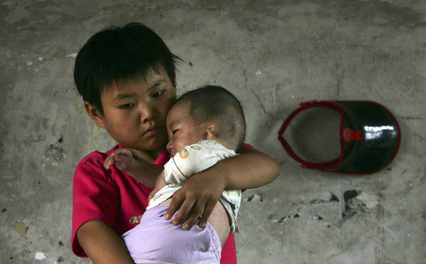 Orphan holding baby orphan in China orphanage