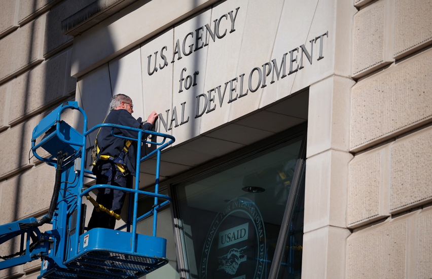 A worker removes the U.S. Agency for International Development sign on their headquarters