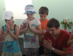 Alexei Yuditsenko, Mission Eurasia’s School Without Walls (SWW) coordinator in Berdyansk, praying with children in Ukraine.