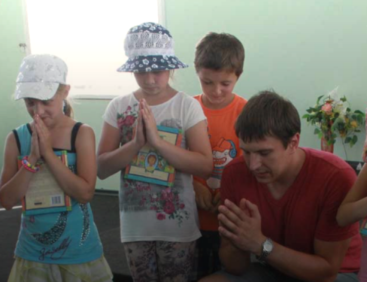 Alexei Yuditsenko, Mission Eurasia’s School Without Walls (SWW) coordinator in Berdyansk, praying with children in Ukraine.