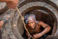 A sanitation worker in Pakistan performs duties without protective gear, highlighting the unsafe and hazardous conditions many face daily despite legal labor protections.