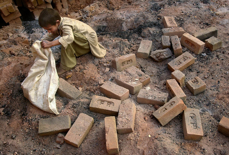 A young boy gathers bricks from the kiln at a brick factory October 24, 2001 outside of Peshawar, Pakistan. Bonded labor that includes children is a major challenge for minority communities in Pakistan.