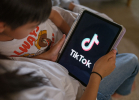 A 7-year-old teenage boy and a 11-year-old teenage girl look at their iPad screen with TikTok logo is displayed on December 07, 2025 in Sydney, Australia