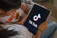 A 7-year-old teenage boy and a 11-year-old teenage girl look at their iPad screen with TikTok logo is displayed on December 07, 2025 in Sydney, Australia