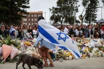 SYDNEY, AUSTRALIA - DECEMBER 15: A mourner wearing an Israeli flag lays flowers at Bondi Beach on December 15, 2025 in Sydney, Australia.