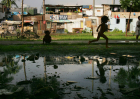 A boy runs near a mud puddle along the railroad tracks where hundreds of poverty stricken live in the slums in a Southeast Asian country.