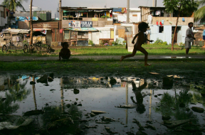 A boy runs near a mud puddle along the railroad tracks where hundreds of poverty stricken live in the slums in a Southeast Asian country.