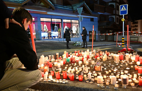 Mourners light candles at the scene after a fire broke out overnight at Le Constellation bar on January 01, 2026 in Crans-Montana, Switzerland.