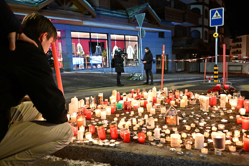 Mourners light candles at the scene after a fire broke out overnight at Le Constellation bar on January 01, 2026 in Crans-Montana, Switzerland.