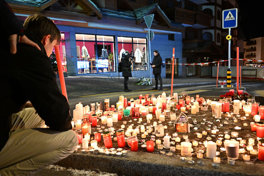 Mourners light candles at the scene after a fire broke out overnight at Le Constellation bar on January 01, 2026 in Crans-Montana, Switzerland.