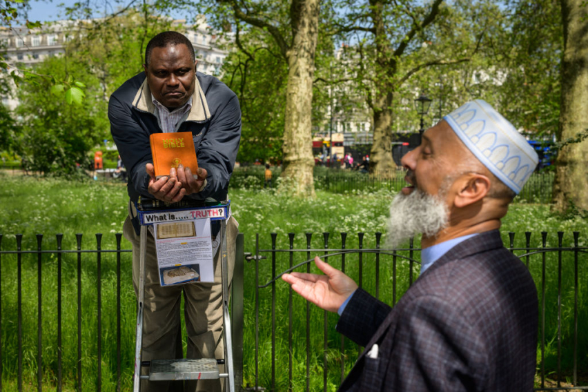 A Christian and a Muslim engage in a public debate at Speaker’s Corner in Hyde Park in London, UK, where open discussions on religion and belief have long been a feature of public life.