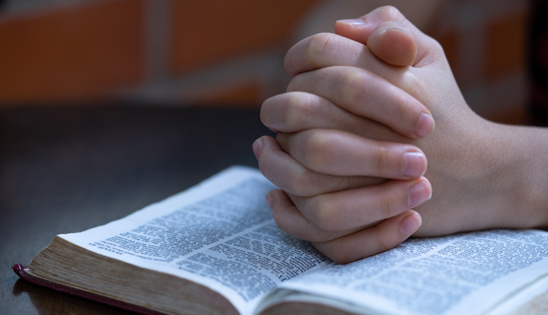 Young prayer on Bible