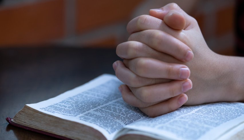 Young prayer on Bible