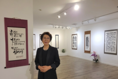 Artist Kim Chang-soon, also known as Laura Kim, stands among her works during her solo exhibition in Los Angeles, which highlighted more than seven decades of calligraphy shaped by faith, perseverance and artistic discipline.
