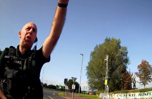 Officer approaches Claire Brennan before arrest outside hospital in Coleraine, Northern Ireland in 2023, before her 2025 arrest at the same site.