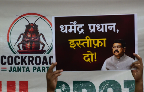 A supporter of the Cockroach Janta Party (CJP) holds placards featuring the groups logo and calling for the resignation of the Education Minister during a protest against alleged examination paper leaks on June 06, 2026 in New Delhi, India