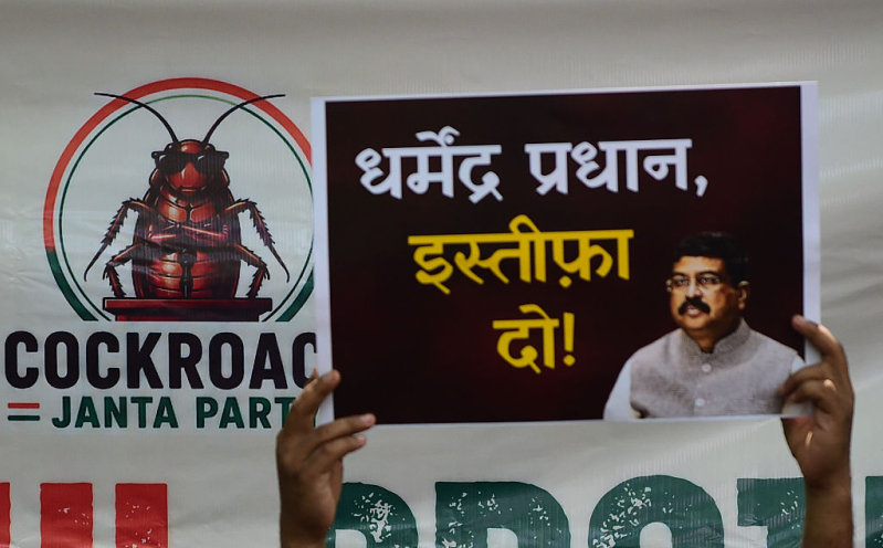 A supporter of the Cockroach Janta Party (CJP) holds placards featuring the groups logo and calling for the resignation of the Education Minister during a protest against alleged examination paper leaks on June 06, 2026 in New Delhi, India