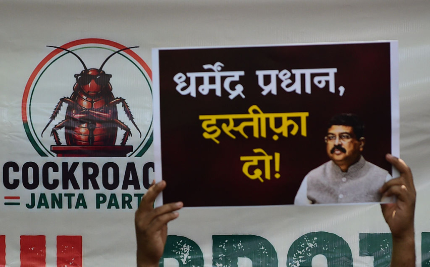 A supporter of the Cockroach Janta Party (CJP) holds placards featuring the groups logo and calling for the resignation of the Education Minister during a protest against alleged examination paper leaks on June 06, 2026 in New Delhi, India