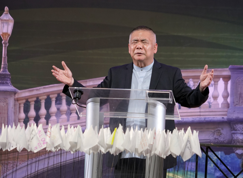 Asia Evangelical Alliance General Secretary Dr. Bambang Budijanto prays over white flags bearing the names of churches delegates committed to help transition toward disciple-making, during the closing ceremony of the Asia Conference on Church & Mission 20