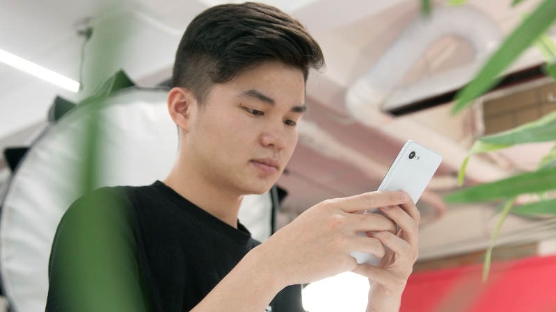 A young adult consults his phone