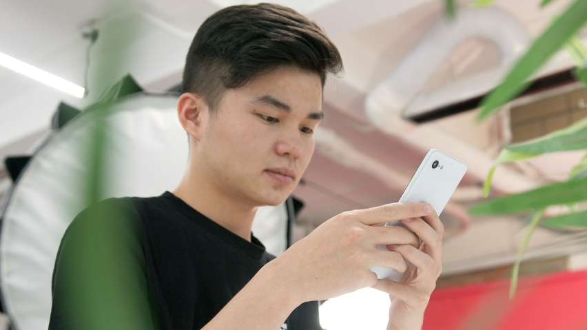 A young adult consults his phone