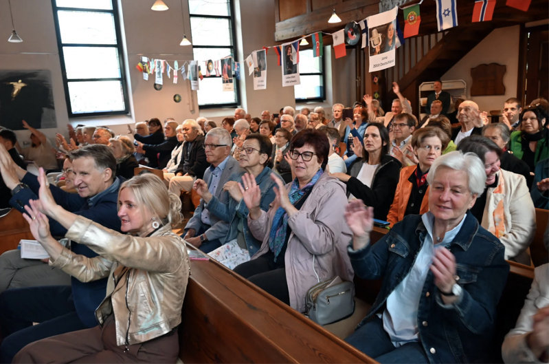 Congregants clap and raise their hands during a Schlager Gottesdienst at Christuskirche in Graz-Eggenberg.