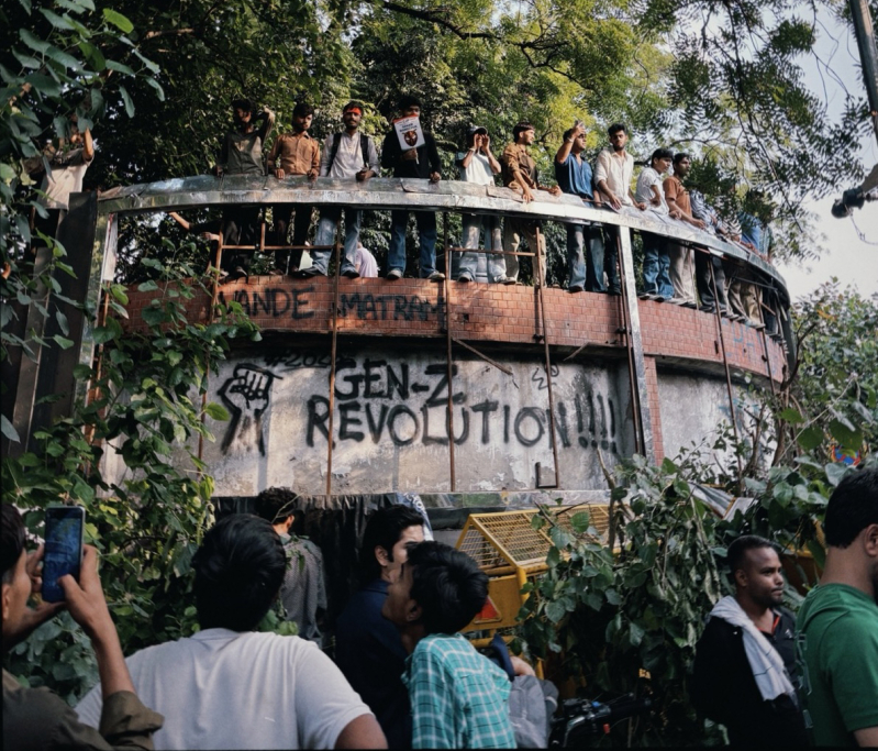 Protesters climb atop a structure spray-painted with Gen-Z Revolution!!! during demonstrations against Indias examination system in Delhi on July 23, 2026. The student-led protests, which spread across the country, demanded accountability from educatio