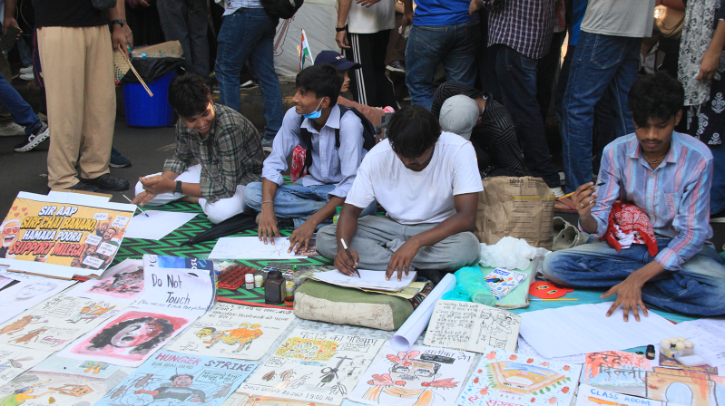 Young protesters create hand-drawn signs at Jantar Mantar in New Delhi during a demonstration organized by the Cockroach Janta Party.