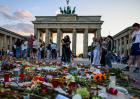 Tourists and visitors observe and pay respects at a makeshift memorial set in Pariser Platz in front of the Brandenburg gate, one week after the Christopher Street Day pride parade attack on August 2, 2026 in Berlin, Germany.