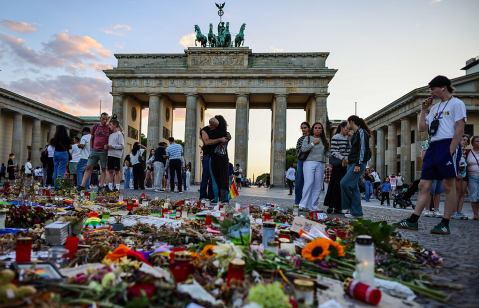 Tourists and visitors observe and pay respects at a makeshift memorial set in Pariser Platz in front of the Brandenburg gate, one week after the Christopher Street Day pride parade attack on August 2, 2026 in Berlin, Germany.