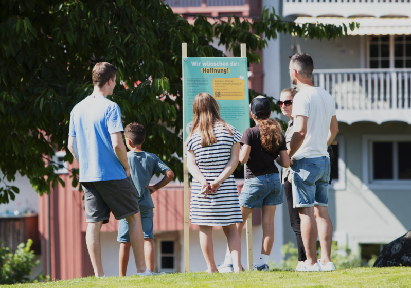 Visitors read a station panel bearing the message Wir wünschen dir: Hoffnung! — We wish you: Hope! — during the LifeTrails pilot in Bischofszell, Switzerland.