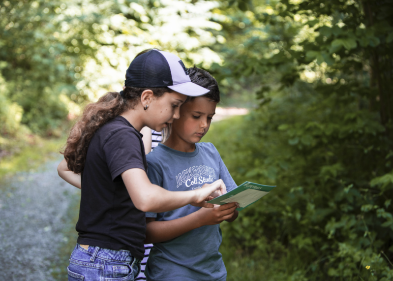 Two young participants consult their scratch card along the Path of Hope trail. Clues at each of the nine stations reveal which fields to scratch off.