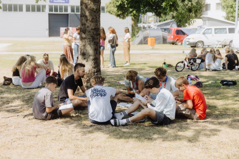 Teenagers gather in small groups on the grass at TeenStreet 2026 in Offenburg, Germany, reading and discussing the Bible together during the Aug. 1–8 conference organized by Operation Mobilisation.