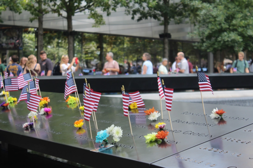 Tourists observe multiple flags among the names of 9/11 victims