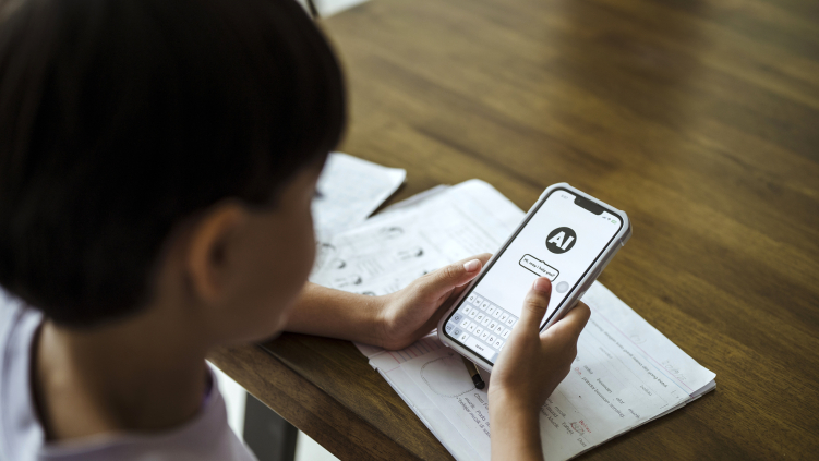 A child uses an artificial intelligence chatbot on a smartphone while doing homework.