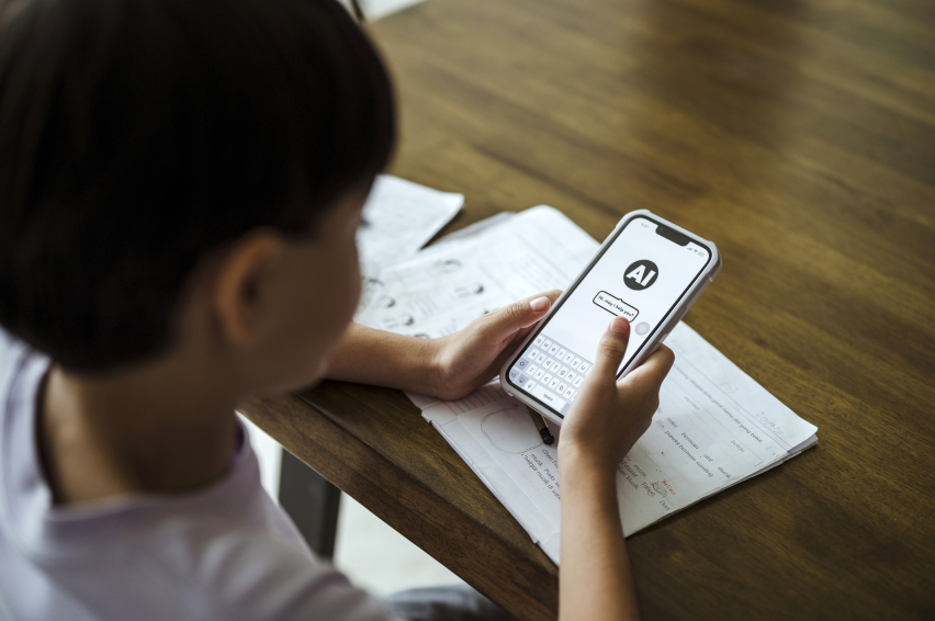 A child uses an artificial intelligence chatbot on a smartphone while doing homework.