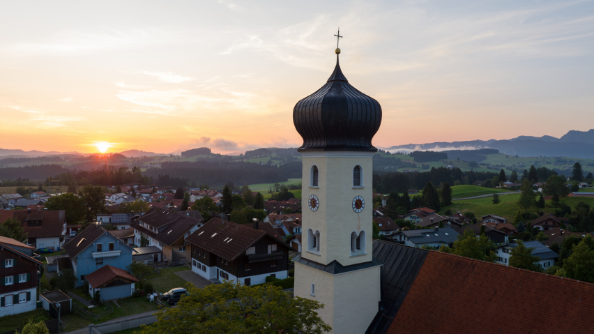 A church tower rises above the village of Oberreute in the Allgäu region of Bavaria, Germany.